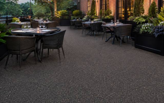 Restaurant patio under string lights finished in brown rubber surfacing.