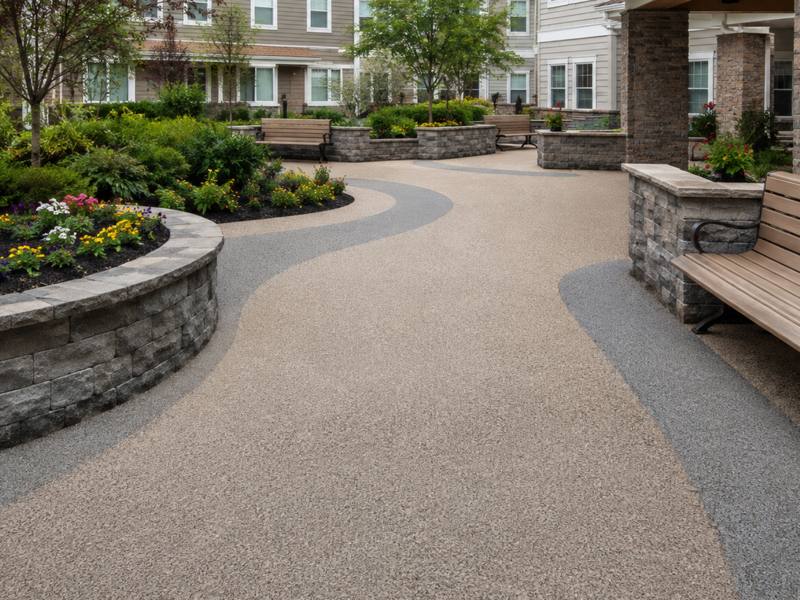 Seniors' residence courtyard path near Oakville poured in rubber surfacing beside wooden benches.